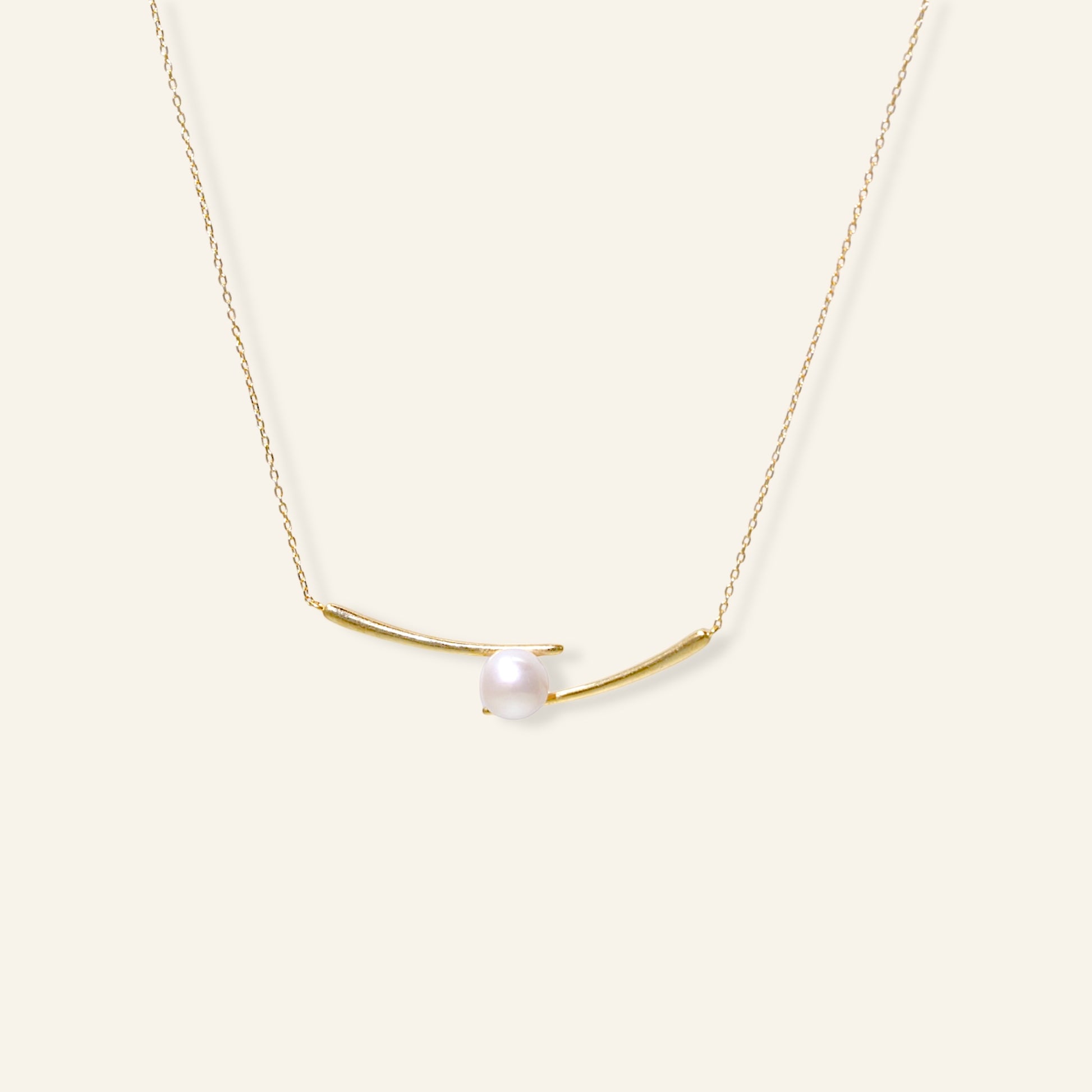 Gold necklace with a single pearl on a white background