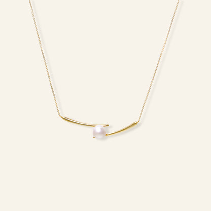 Gold necklace with a single pearl on a white background