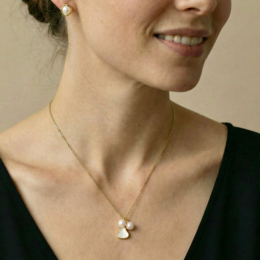 Close-up of a woman wearing a gold necklace with a pearl pendant 
