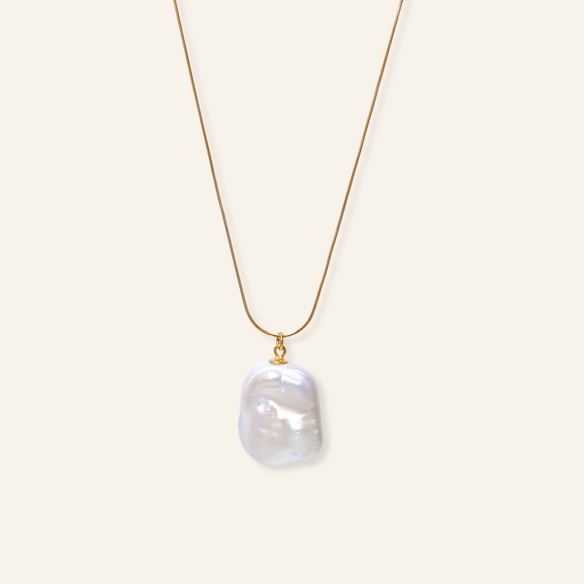 Gold necklace with a large pearl pendant on a white background