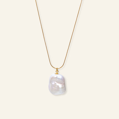 Gold necklace with a large pearl pendant on a white background