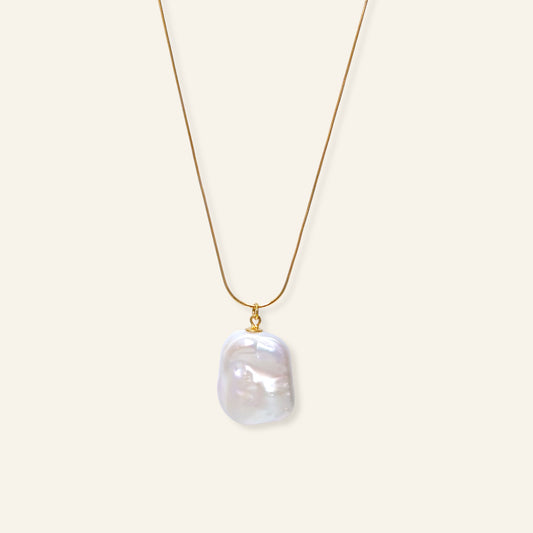 Gold necklace with a large pearl pendant on a white background