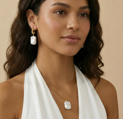 Woman wearing a  pearl necklace and earrings with a neutral background