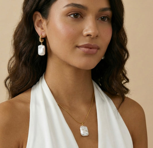Woman wearing a  pearl necklace and earrings with a neutral background