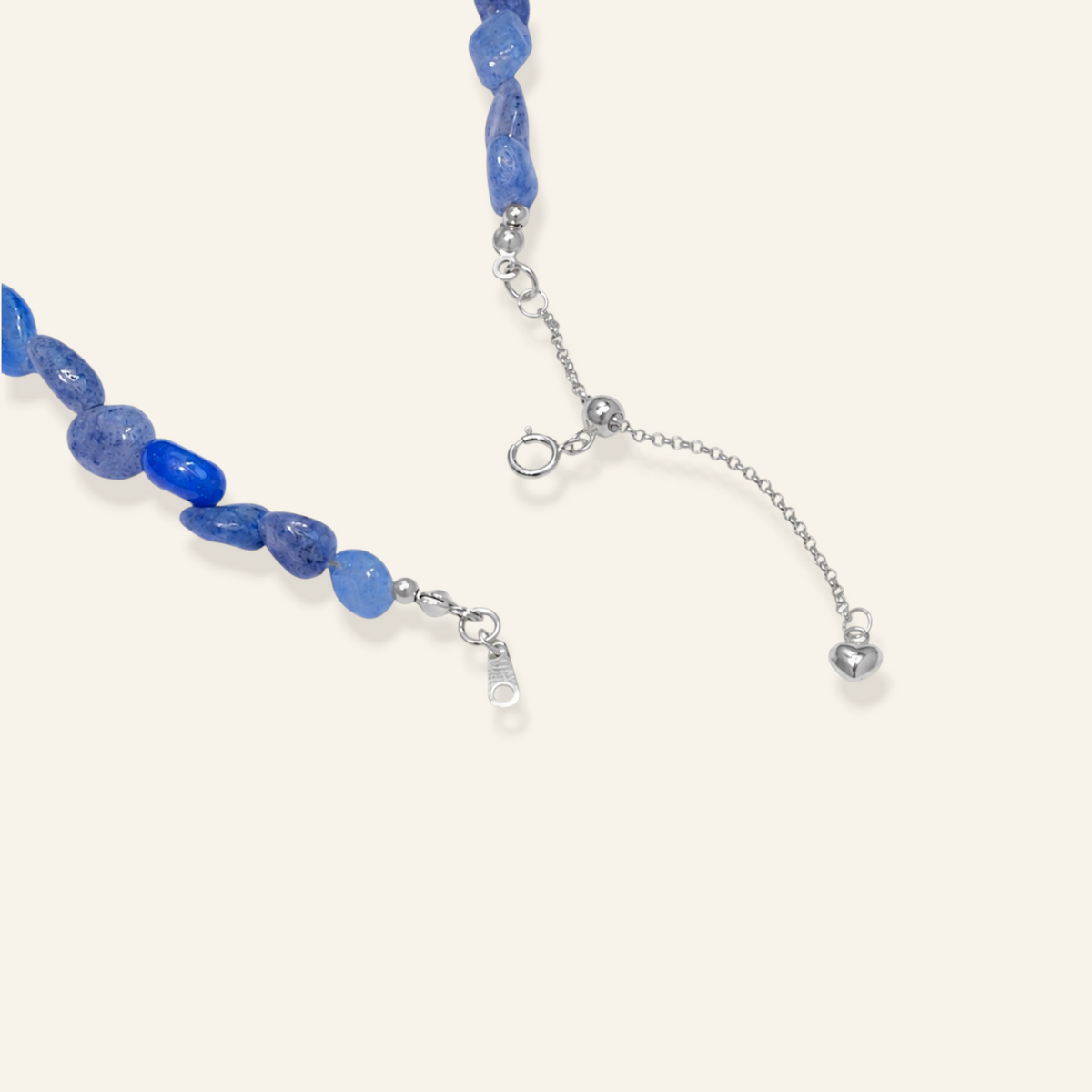 A close-up of a beaded necklace with irregular blue gemstone beads and silver-toned chain hardware, including an extender chain and clasp