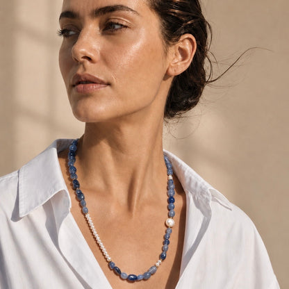 A woman wearing a beaded necklace with blue stone beads, white pearl
