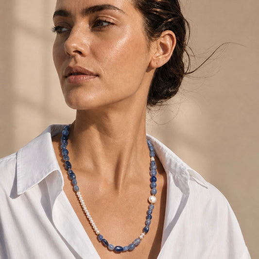 A woman wearing a beaded necklace with blue stone beads, white pearl