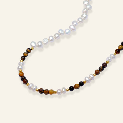 Beaded necklace with white pearls, brown and black beads on a light beige background