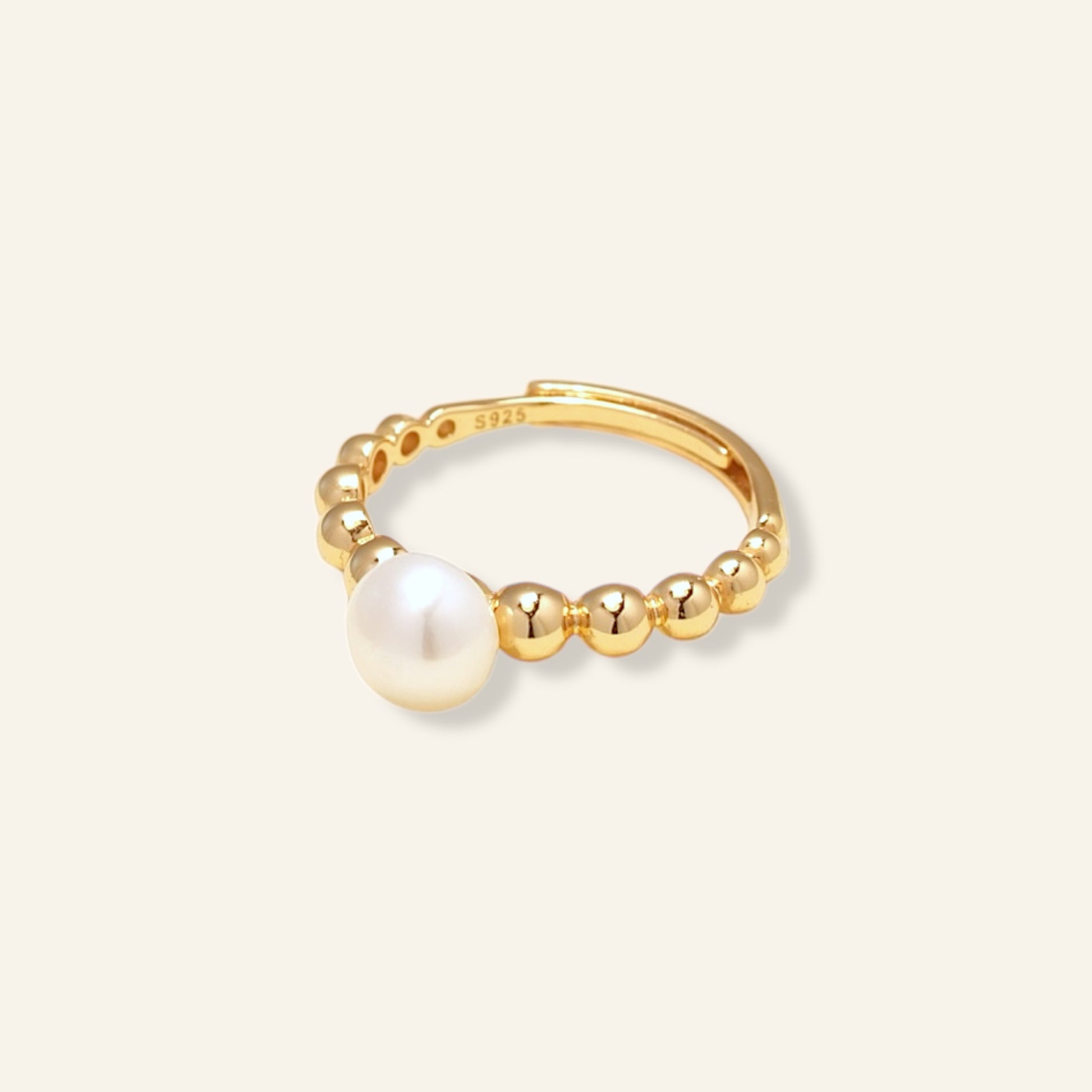 Gold ring with a pearl on a light beige background