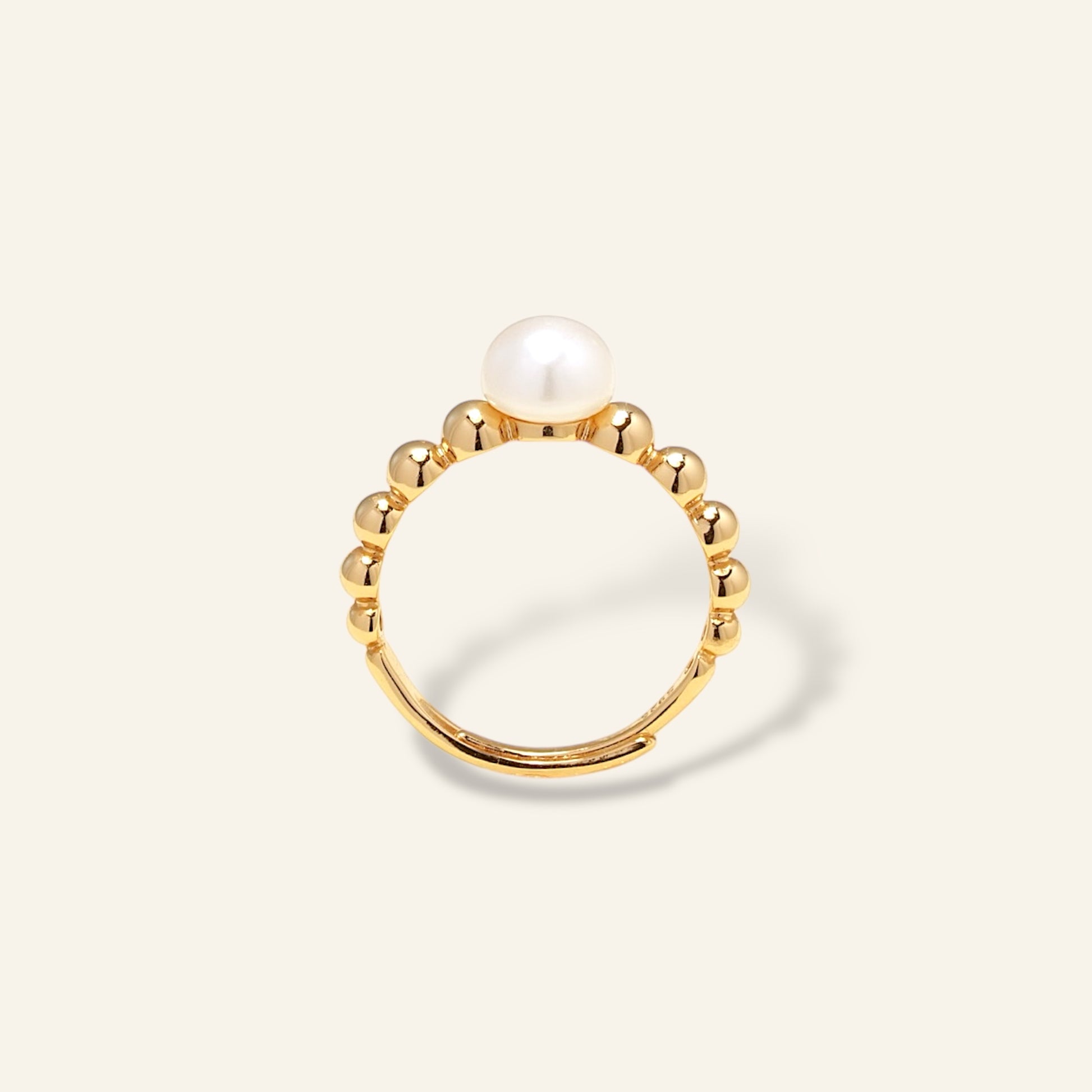 Gold ring with a pearl on a light beige background