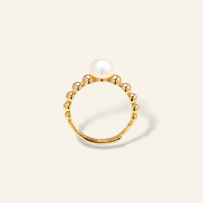 Gold ring with a pearl on a light beige background