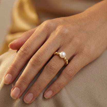 Hand wearing a gold ring with a pearl 