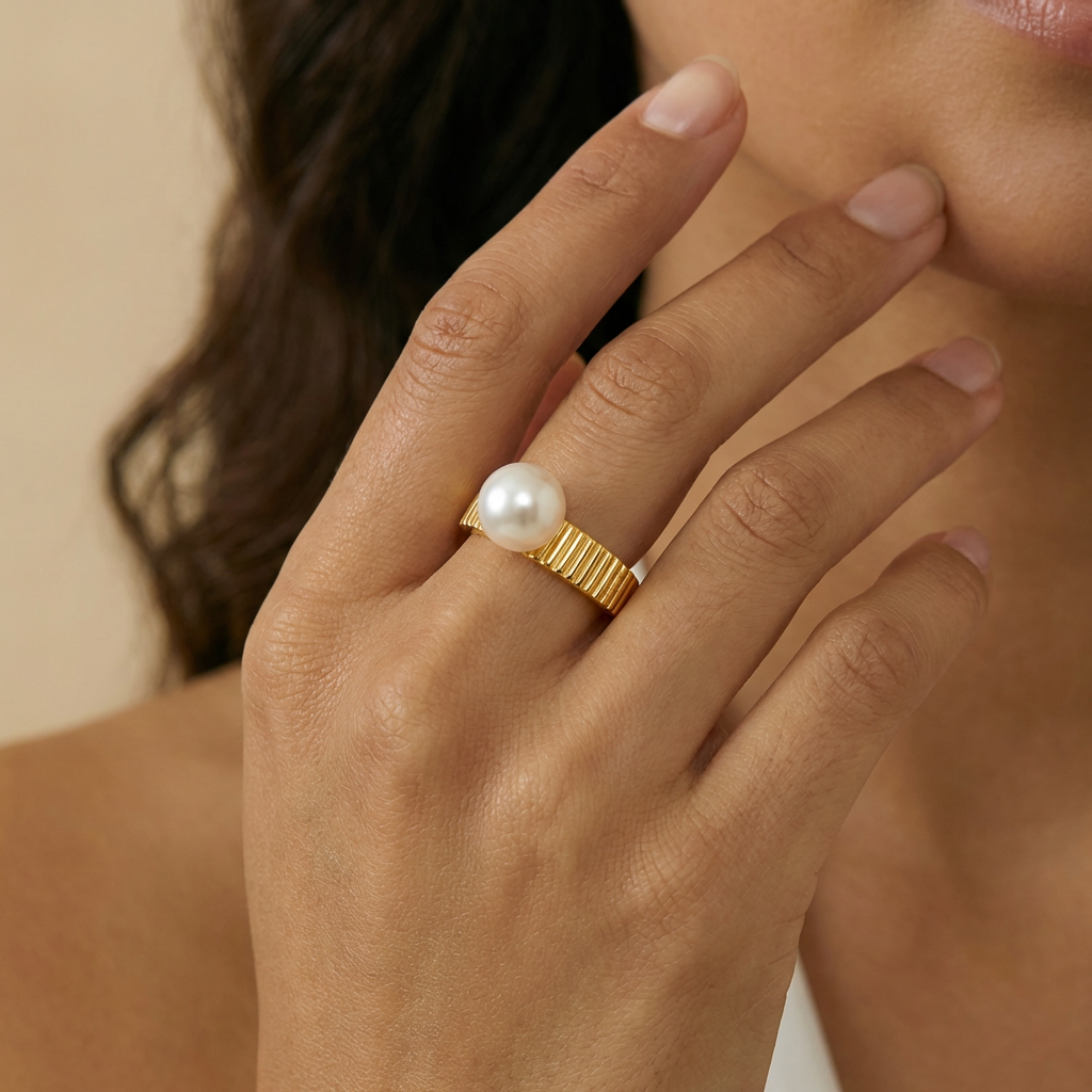 Hand wearing a gold ring with a pearl