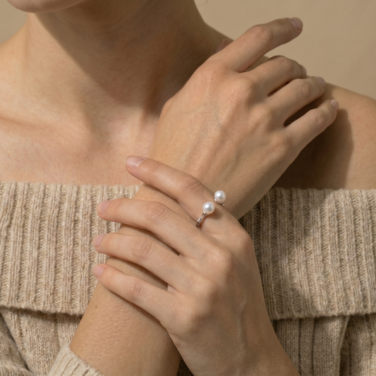 Close-up of a person wearing a pearl ring on a neutral background