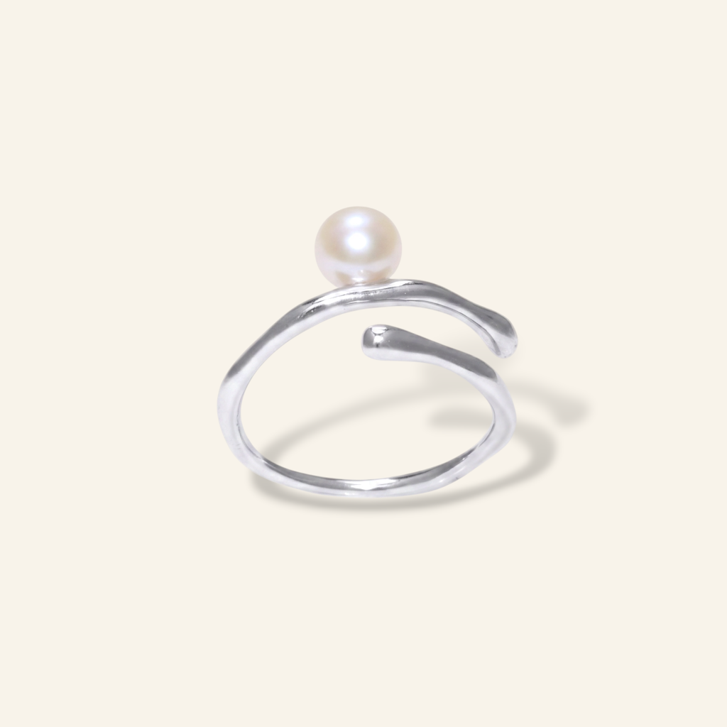 Silver ring with a pearl on a light beige background