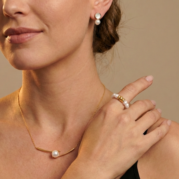 Close-up of a woman wearing pearl jewelry including earrings, necklace, and pearl ring 
