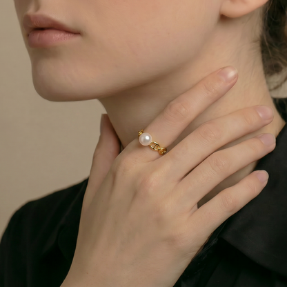 Woman wearing a gold ring with a pearl on a neutral background