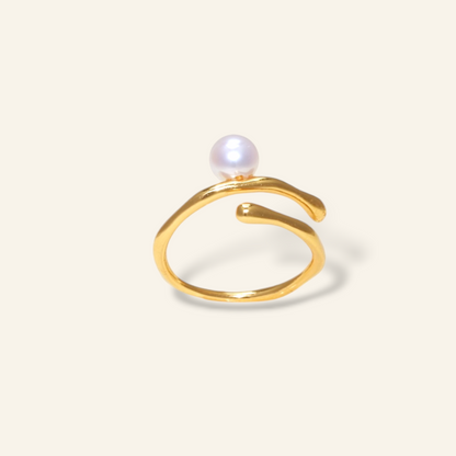 Gold ring with a pearl on a light beige background