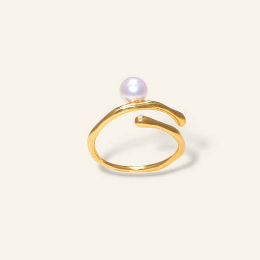 Gold ring with a pearl on a light beige background