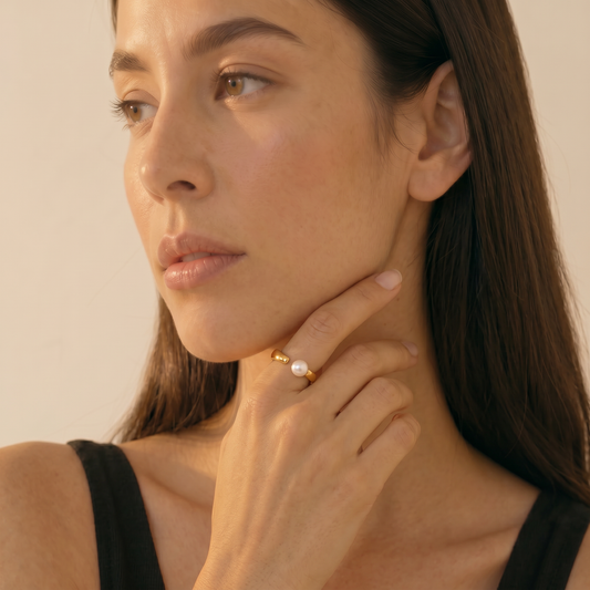Woman wearing a pearl ring with a neutral background