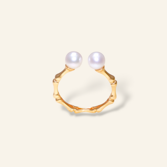 Gold ring with two pearls on a light beige background
